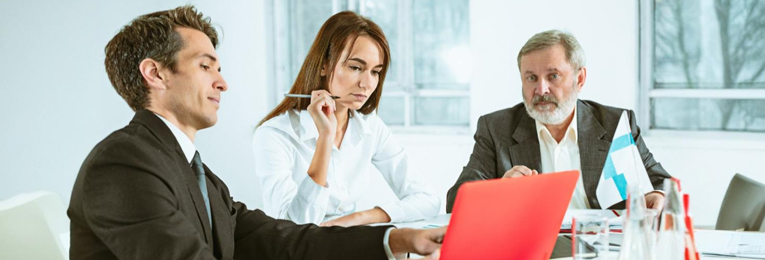 An illustrative image of three people engaged in a discussion in an office boardroom.